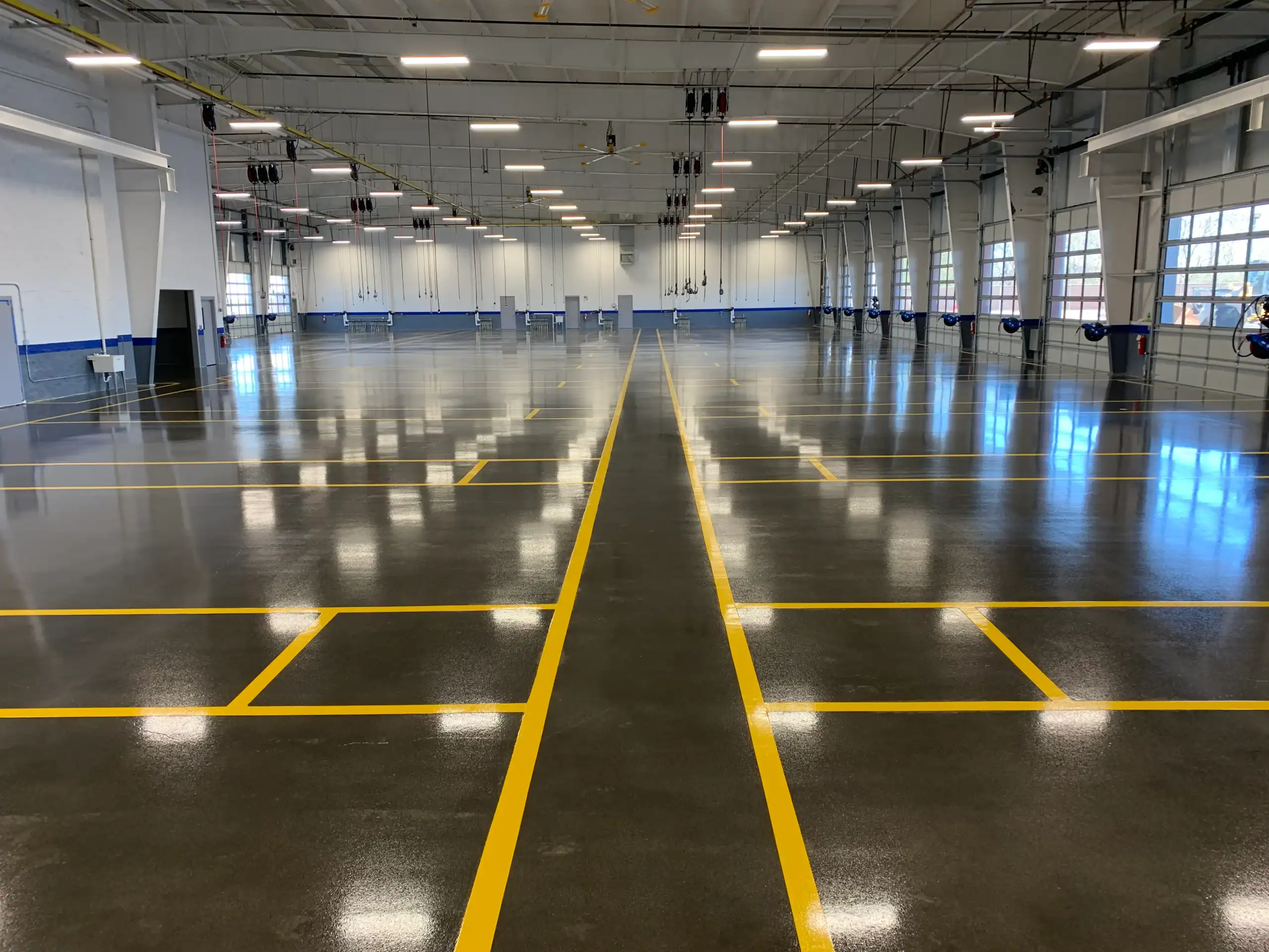 An empty indoor NY parking garage features shiny epoxy floors and bright overhead lights.
