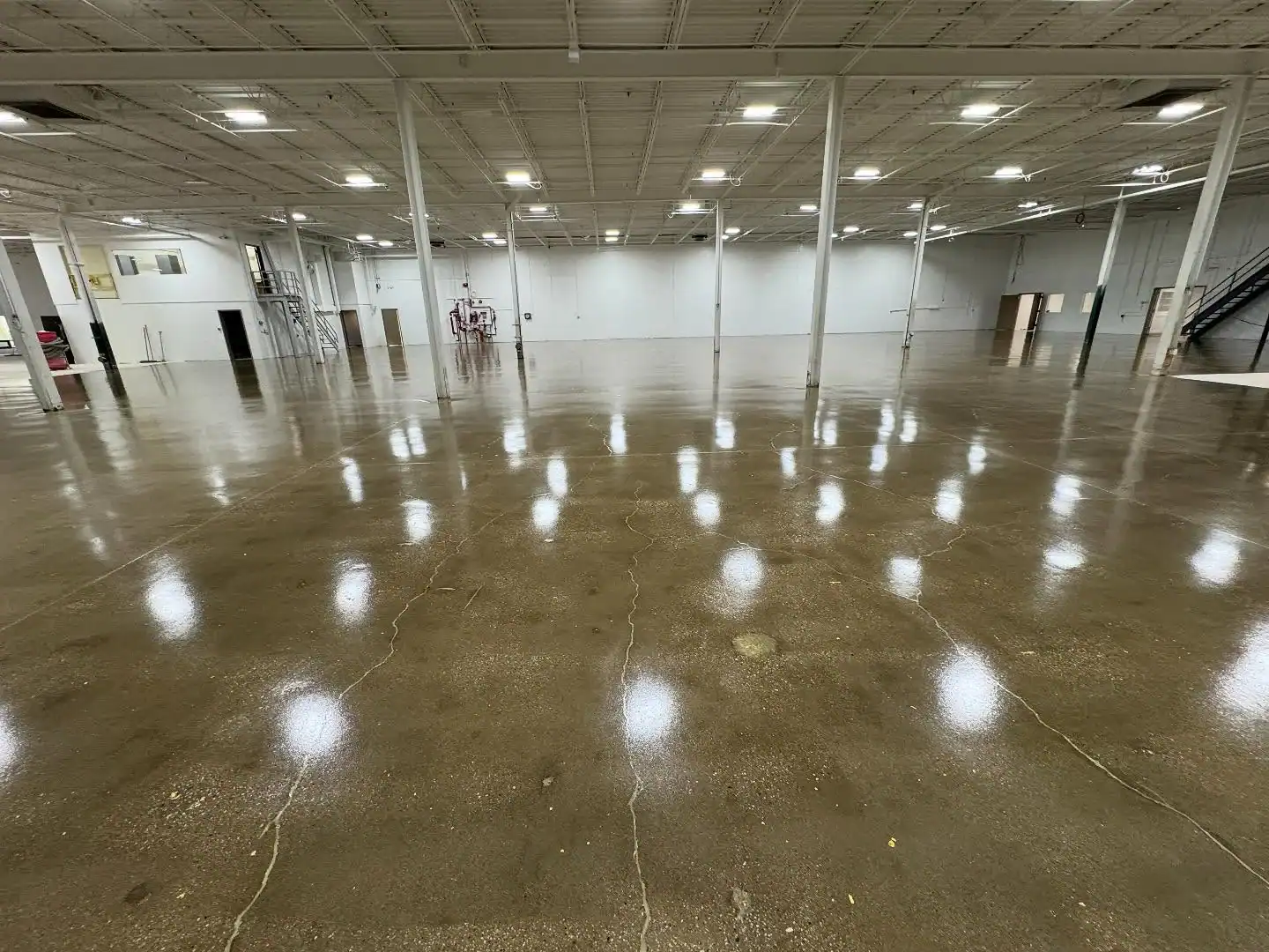 Empty NY warehouse with polished concrete floors by Epoxy Flooring Contractor Bohemia, lights above.