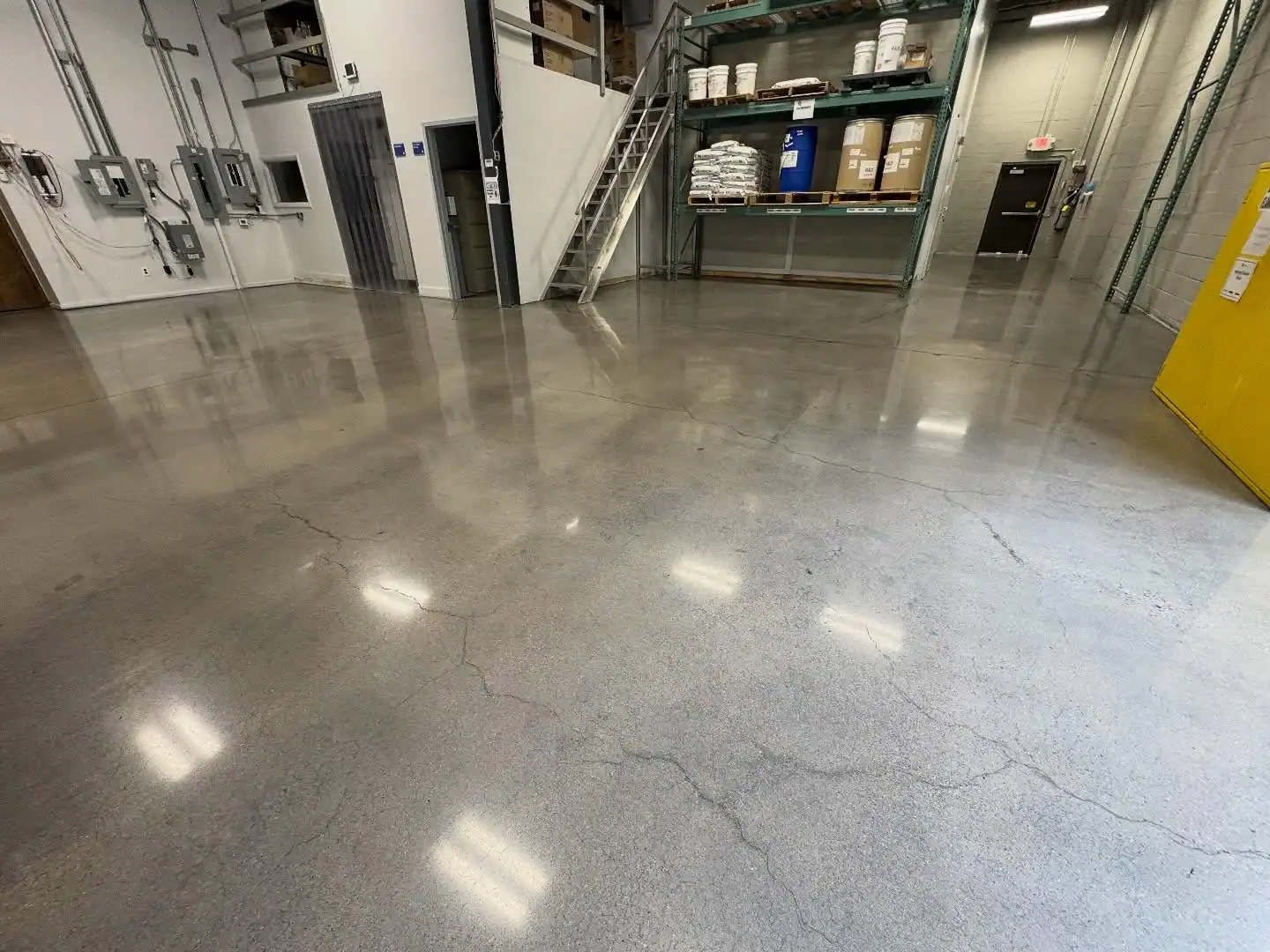 Polished epoxy floors in an industrial warehouse by a Bohemia, NY contractor, shelving in the back.