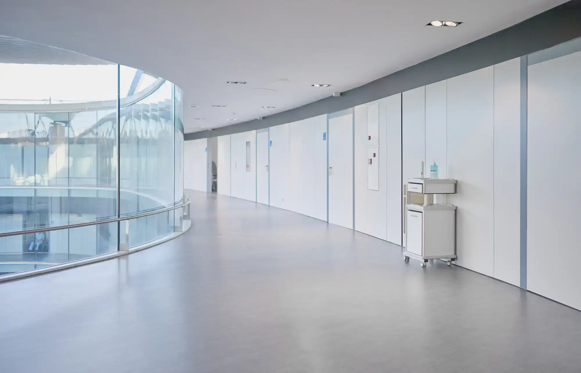 Modern, empty NY hospital hallway with a curved glass wall and Epoxy Flooring Contractor Bohemia design.
