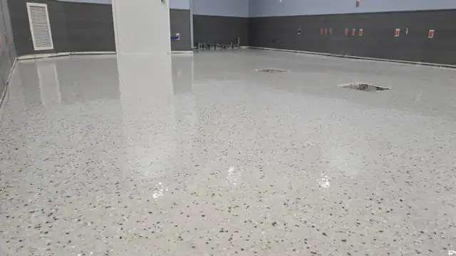 A shiny, polished concrete floor by Epoxy Flooring Contractor Bohemia glistens in an empty gray-walled NY room.