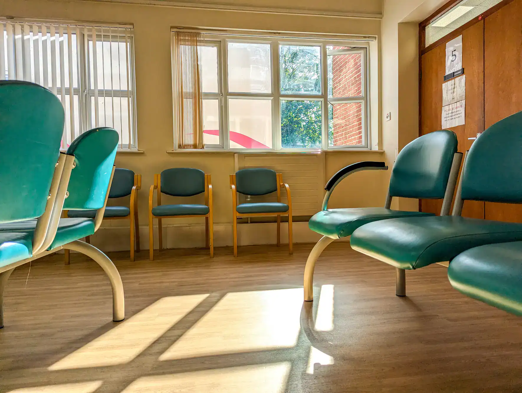 Empty waiting room featuring green and wood chairs, sunlight on epoxy floor by NY Epoxy Flooring Contractor.