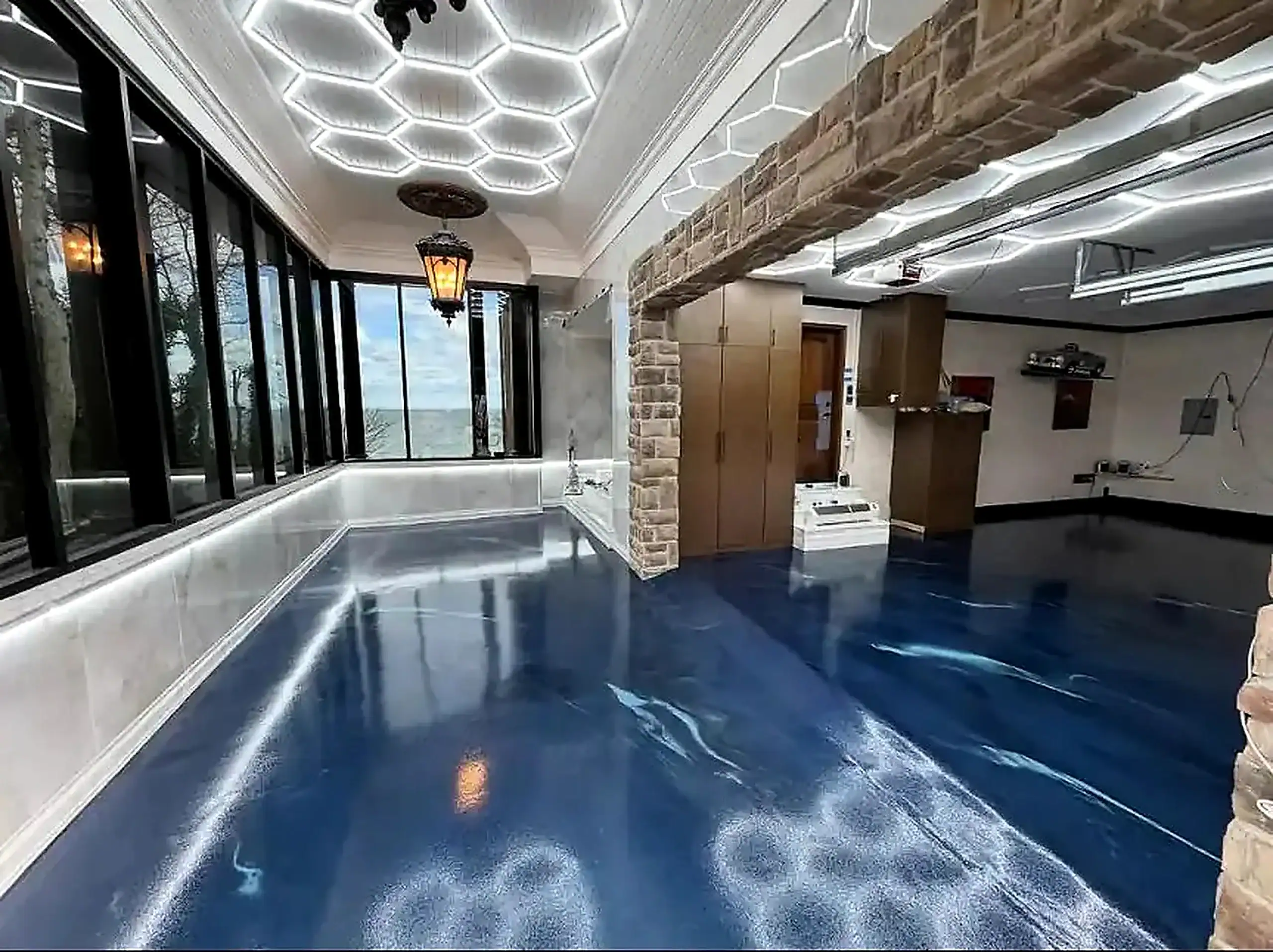 Room featuring glossy blue epoxy flooring by Contractor Bohemia, NY, with a stone archway and hex lights.