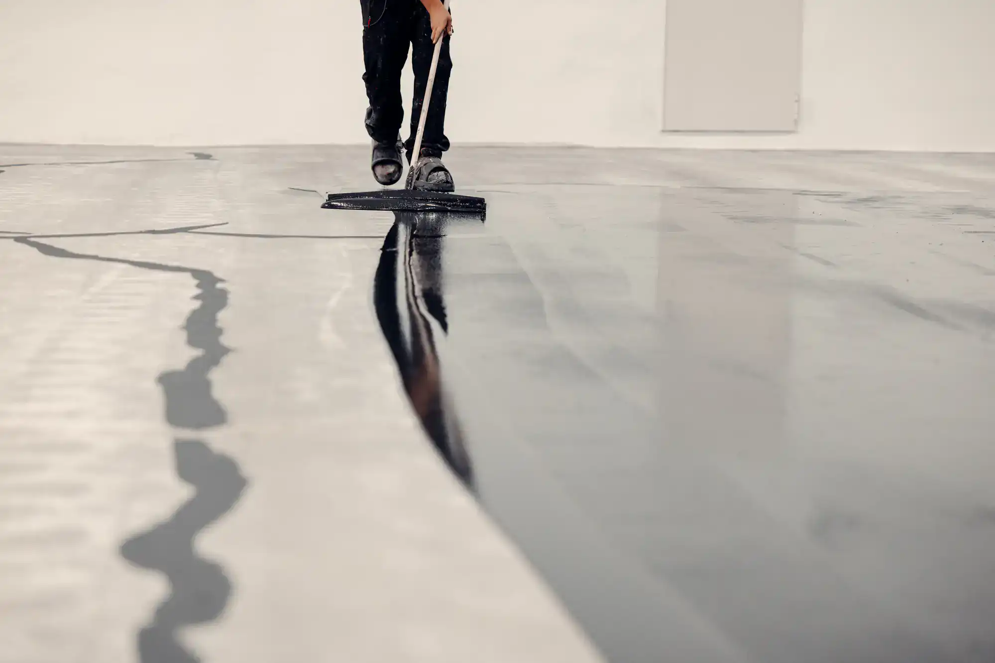 An Epoxy Flooring Contractor in Bohemia expertly applies epoxy coating to a sunlit NY concrete floor.