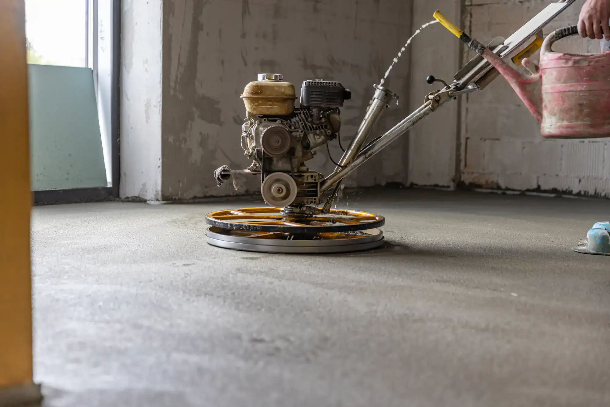 A construction worker from Epoxy Flooring Contractor Bohemia smooths wet concrete on an indoor NY floor.