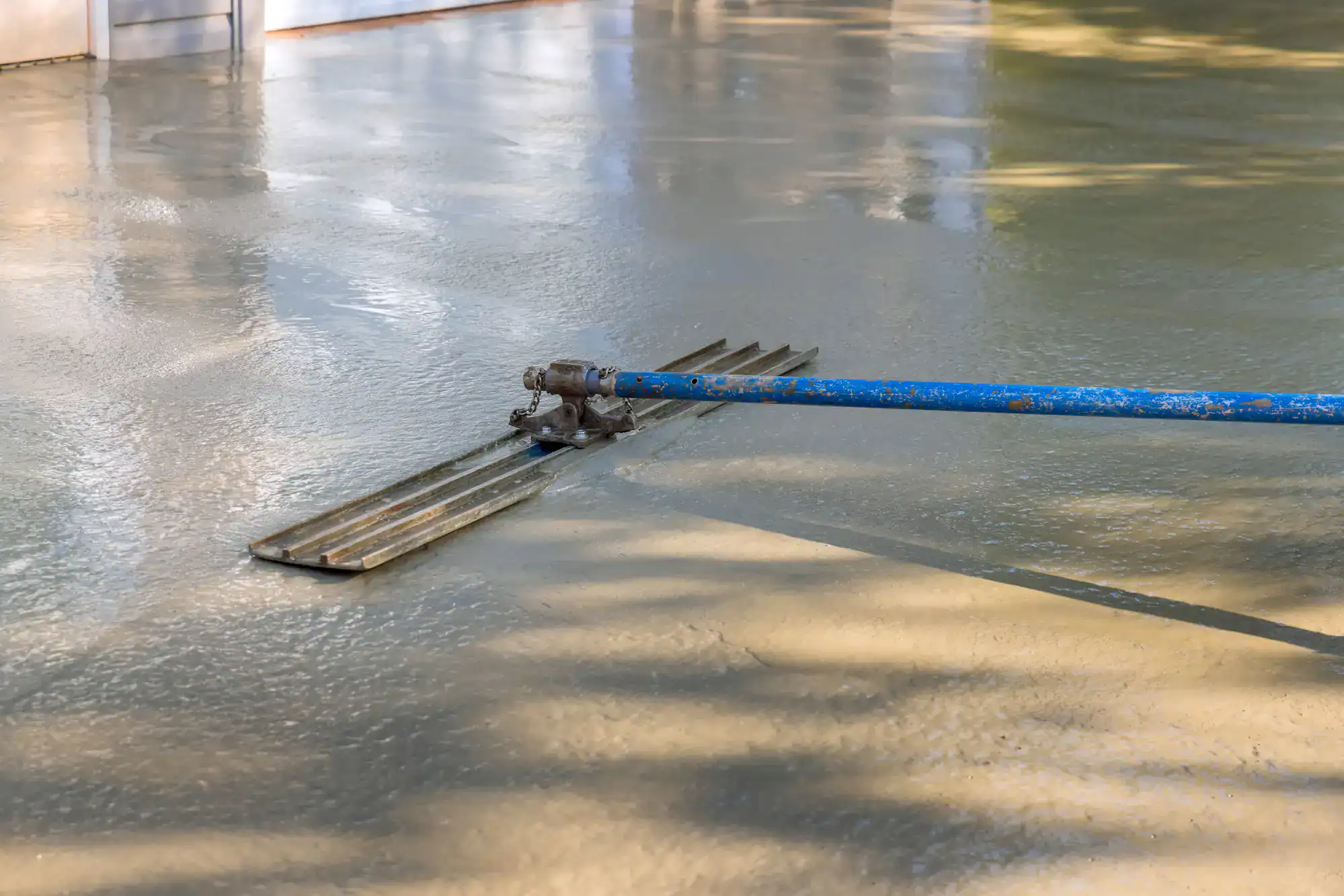 A bull float glides over wet concrete, achieving a smooth finish for an Epoxy Flooring Contractor in Bohemia, NY.
